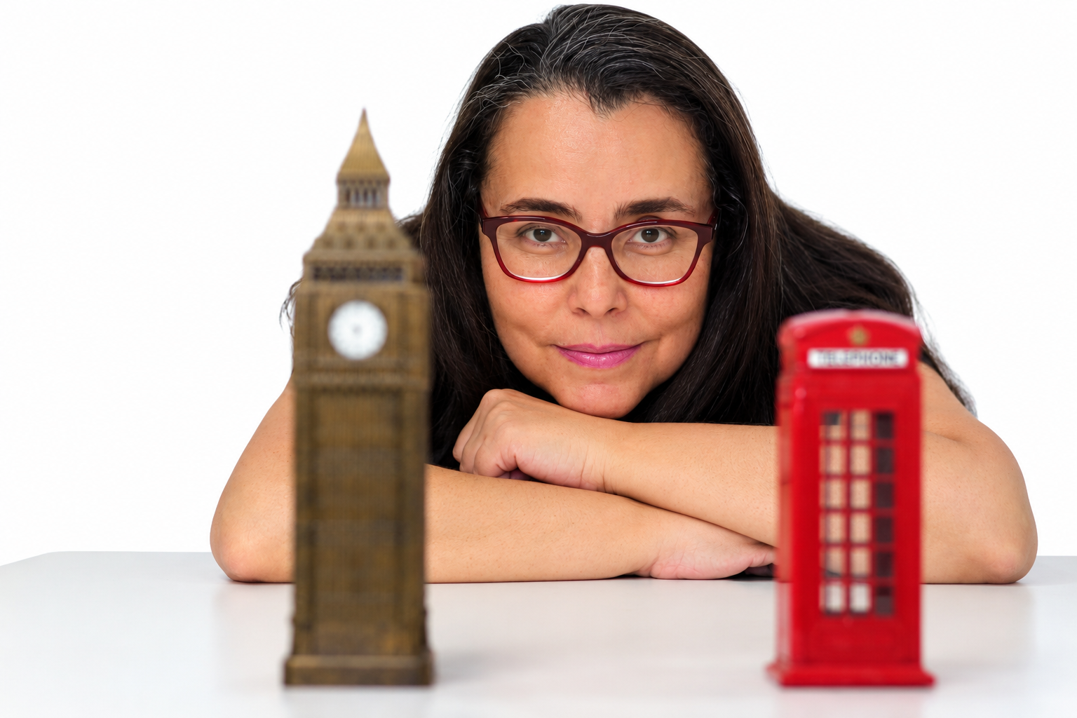 Luciana Nappi apoiada em uma mesa, entre miniaturas do Big Ben e de uma cabine telefônica de Londres